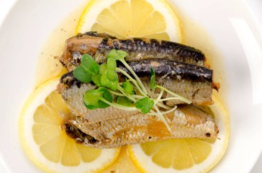 Beyaz tabakta dilimlenmiş limonlu sardalyalar. 