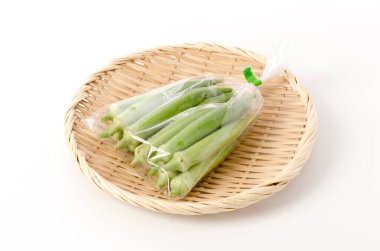 Beyaz arka planda bambu elek üzerinde plastik bir torba içinde taze bamya