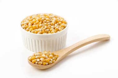 Kokotta patlamamış patlamış mısır tohumları ve beyaz arka planda kaşık.