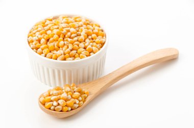 Kokotta patlamamış patlamış mısır tohumları ve beyaz arka planda kaşık.