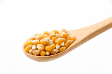 Beyaz arka planda tahta kaşıkta patlamış mısır tohumları