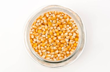 Beyaz zemin üzerinde şeffaf cam kavanozda patlamış mısır tohumları