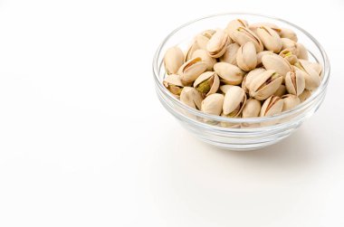 Beyaz arka planda cam bir kasede fıstık.