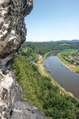Dresden ve Elbe nehri kıyısındaki ulusal parktaki Kurort Rathen köyü yakınlarındaki anıtsal Bastei kumtaşı sütunları üzerinde kuş bakışı kapak sayfası, mavi gökyüzü, Saksonya, Almanya