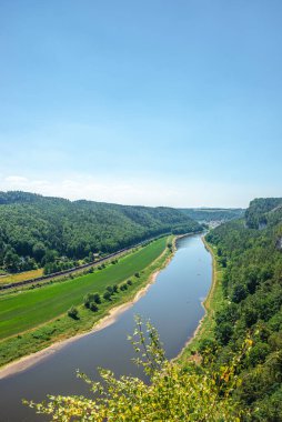 Dresden ve Elbe nehri kıyısındaki ulusal parktaki Kurort Rathen köyü yakınlarındaki anıtsal Bastei kumtaşı sütunları üzerinde kuş bakışı kapak sayfası, mavi gökyüzü, Saksonya, Almanya