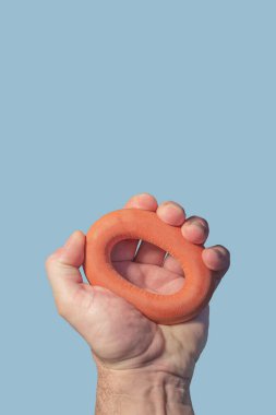 Mavi gökyüzü arka planında kırmızı lastik bir bileğe baskı yapan ve fotokopi alanı olan bir adamın kapak sayfası. Sağlık, spor ve aktif yaşam tarzı kavramı