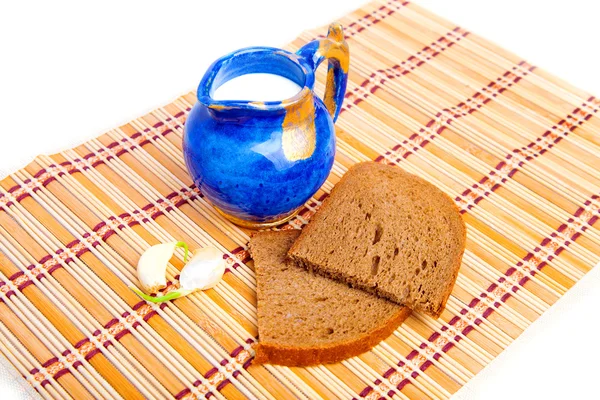 Bread, garlic, and milk on kitchen mat Stock Picture