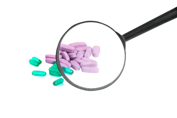 Vihreä ja violetti pillereitä kautta suurennuslasi — kuvapankkivalokuva