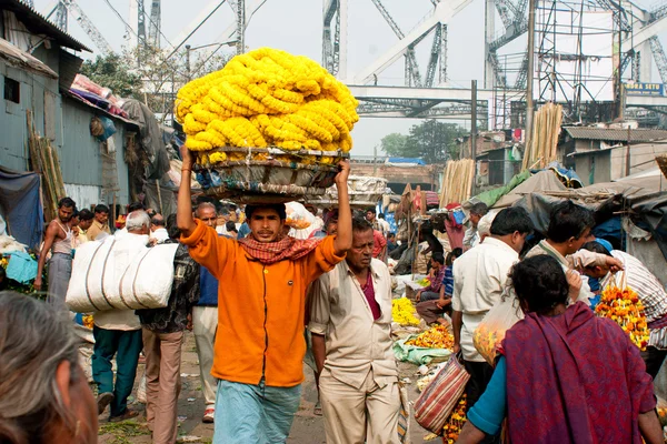 Trabalhador com um carrinho na cabeça no mercado de flores — Fotografia de Stock