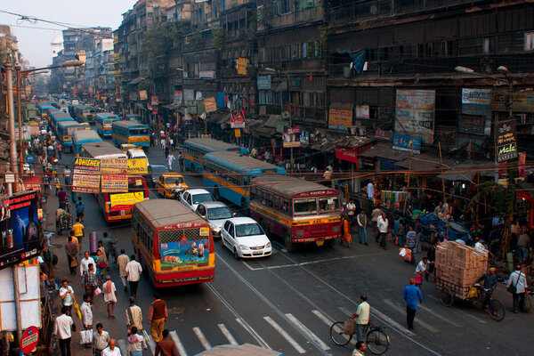 Pedestrians cross the road in front of motorcycles, cars and buses at the crossroads