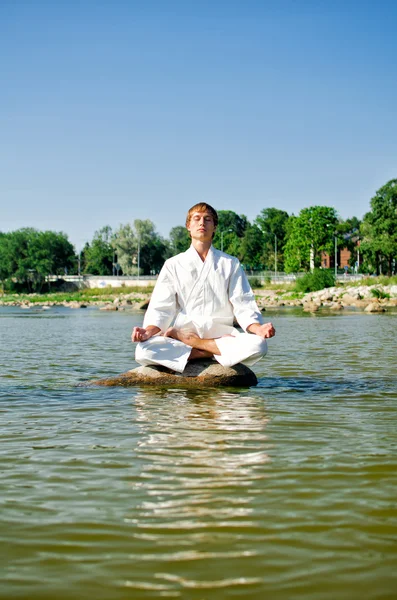 Man in kimono meditating on the rock in the sea — Stock Photo, Image