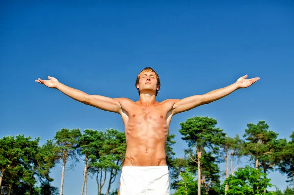 Jonge man doen meditatie oefeningen op hemelachtergrond — Stockfoto