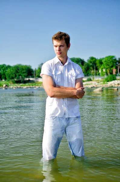 Красивий молодий хлопець стоїть в морі в джинсах — стокове фото