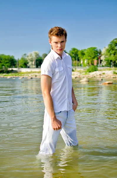 Schöner junger Kerl, der in Jeans im Meer steht — Stockfoto