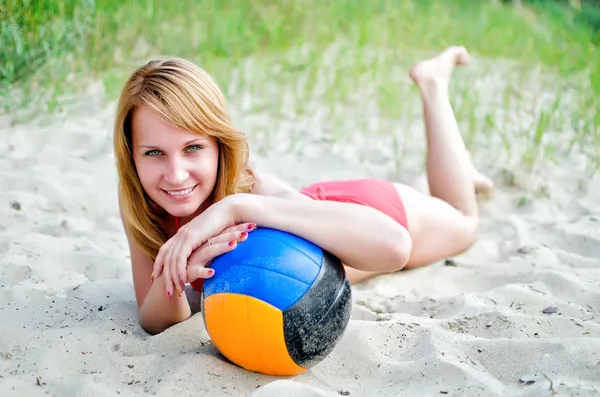 Vacker kvinna med bollen ligga på stranden — Stockfoto