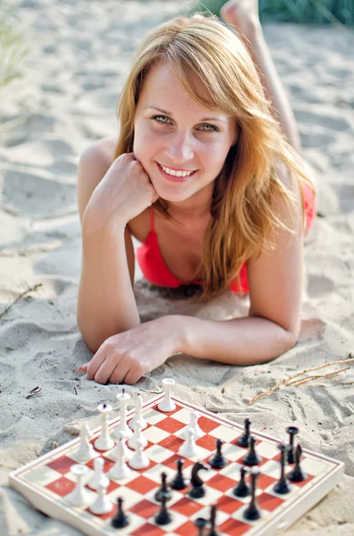 Retrato de una mujer bonita jugando al ajedrez en la playa — Foto de Stock