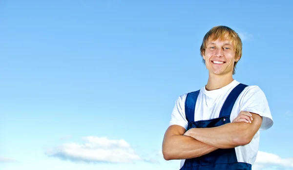 Lächelnder Handwerker in Overalls auf Himmelshintergrund — Stockfoto