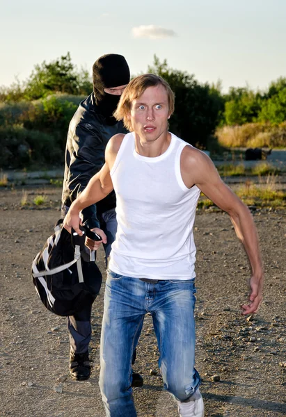 Thief in mask stealing a backpack — Stock Photo, Image
