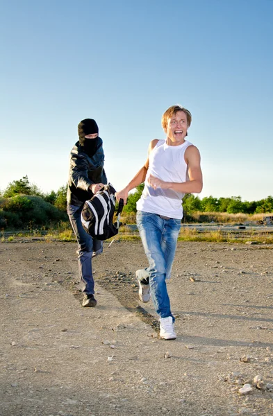 Thief in mask stealing a backpack — Stock Photo, Image