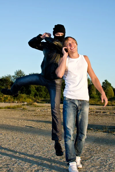 Bandido na máscara tentando roubar o jovem — Fotografia de Stock