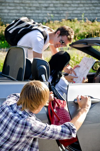 Dieb stiehlt Handtasche aus Auto, während Komplize ihn ablenkt — Stockfoto