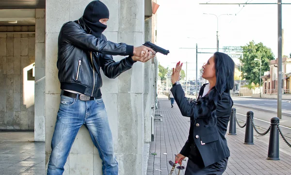 Бандит с пистолетом, угрожающим молодой женщине на улице — стоковое фото