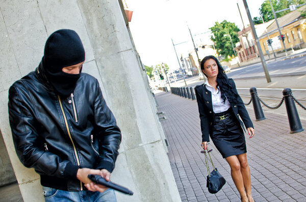 Bandit in mask with gun waiting for victim
