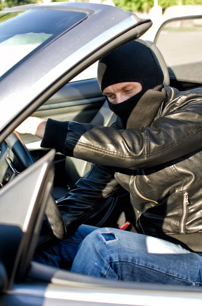 Bandit in mask stealing a car. Royalty Free Stock Images