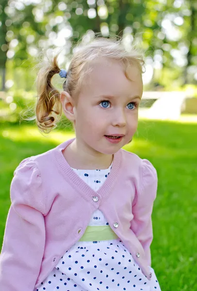 Porträtt av en liten underbar flicka sitter i parken — Stockfoto