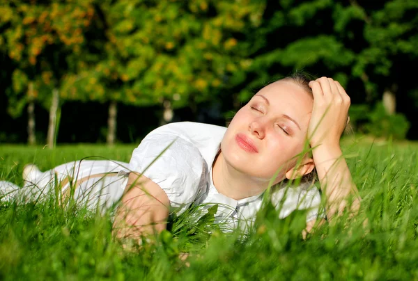 Jovem mulher relaxante na grama no parque — Fotografia de Stock