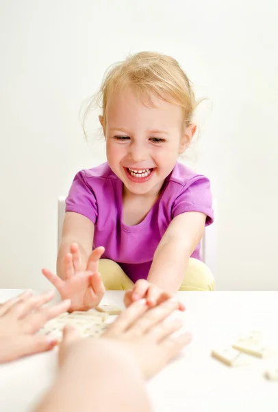 Söt liten flicka med mamma spelar domino vid bordet — Stockfoto