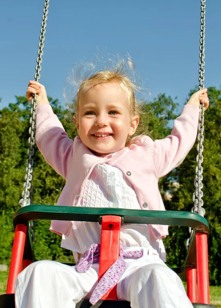 Smiling little girl on swing in the park — Stock Photo, Image