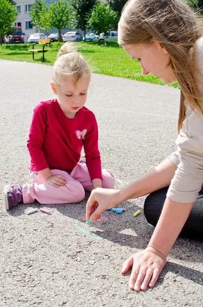 Mutter und Tochter zeichnen mit Kreide auf Asphalt — Stockfoto