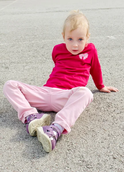 Cute little girl sitting on asphalt — Stock Photo, Image