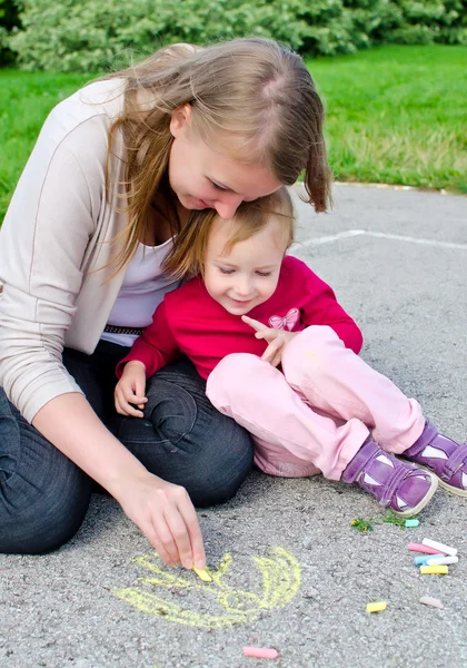 Mother and daughter drawing with chalk on asphalt — Stock Photo, Image
