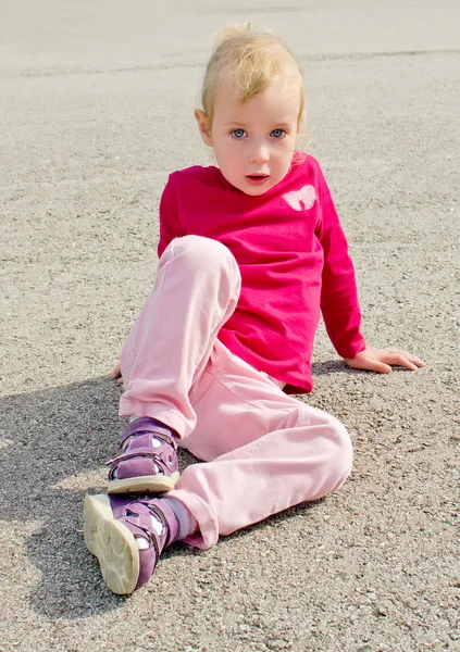 Nettes kleines Mädchen sitzt auf Asphalt — Stockfoto