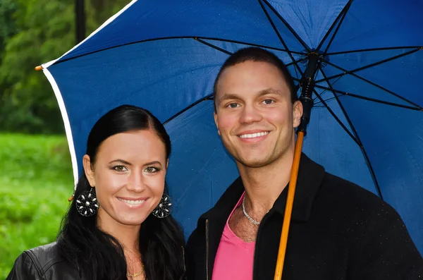 Porträt eines jungen Paares unter einem Regenschirm im Park — Stockfoto