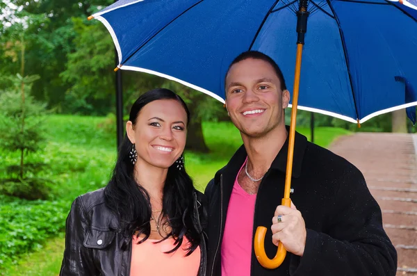 Porträt eines jungen Paares unter einem Regenschirm im Park — Stockfoto