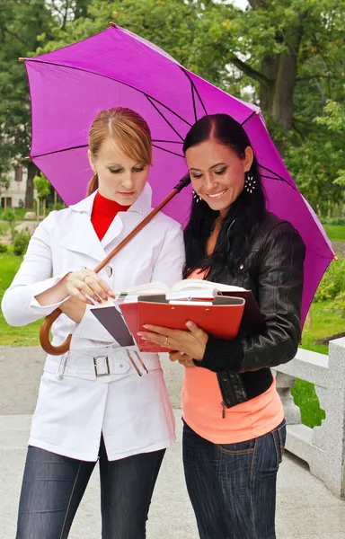 Zwei Studentinnen unter einem Regenschirm im Freien — Stockfoto