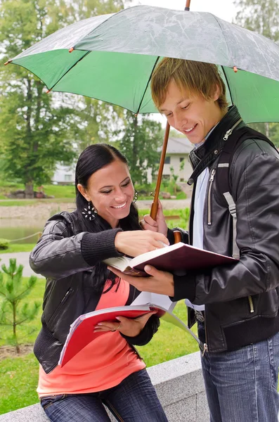 Two students under umbrella in the park — Stock Photo, Image