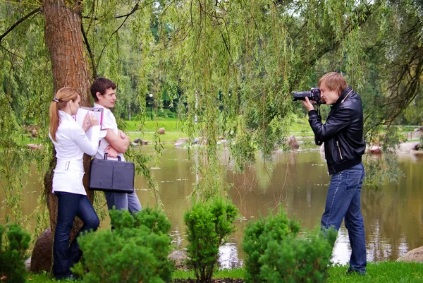 カメラマンは屋外の若いカップルの写真を撮る — ストック写真