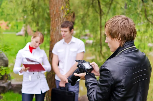 Fotógrafo tira foto de jovem casal ao ar livre — Fotografia de Stock