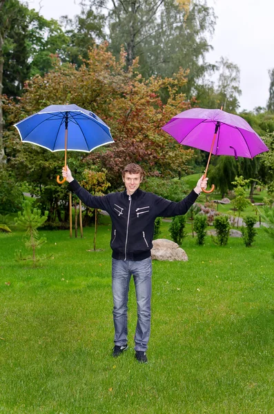 Młody człowiek z zewnątrz dwa parasole — Zdjęcie stockowe