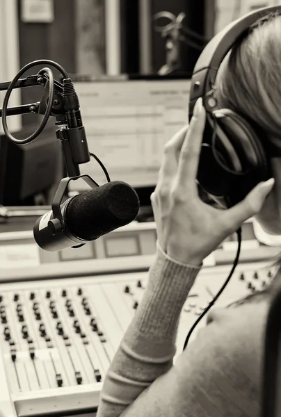 Vista trasera de la hembra dj trabajando delante de un micrófono en la radio. Blach. — Foto de Stock