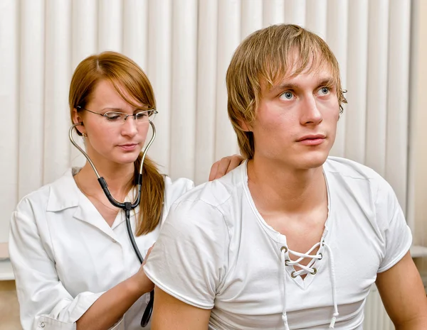 Ung kvinnlig läkare undersöka manlig patient med stetoskop — Stockfoto