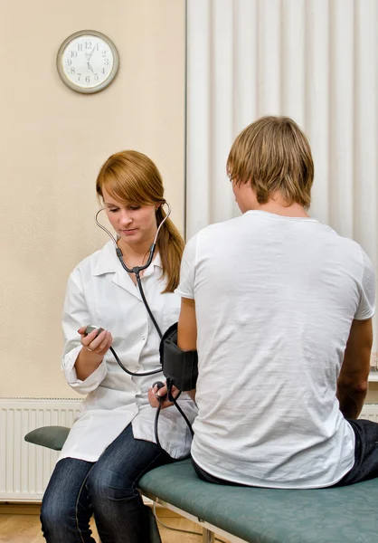 Doctora joven midiendo paciente —  Fotos de Stock