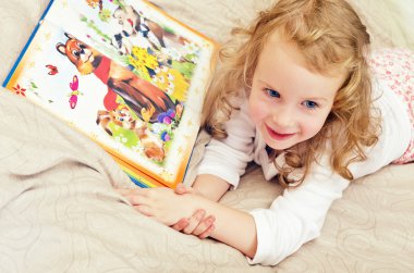 sevimli küçük kız yatakta kitap ile yalan