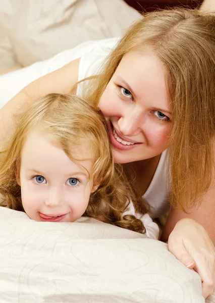 Portrait of young woman and little girl lying in bed — Stock Photo, Image