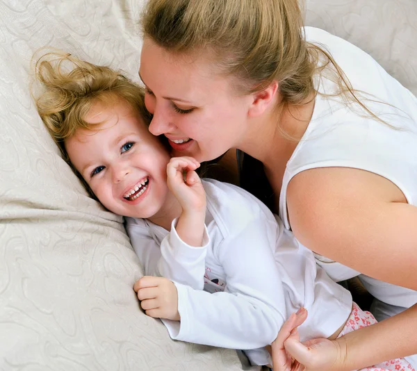 Молодая женщина и маленькая девочка веселятся в постели — стоковое фото