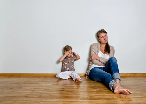 Mutter und Tochter streiten sich, sitzen auf dem Boden und schauen zur Seite. — Stockfoto